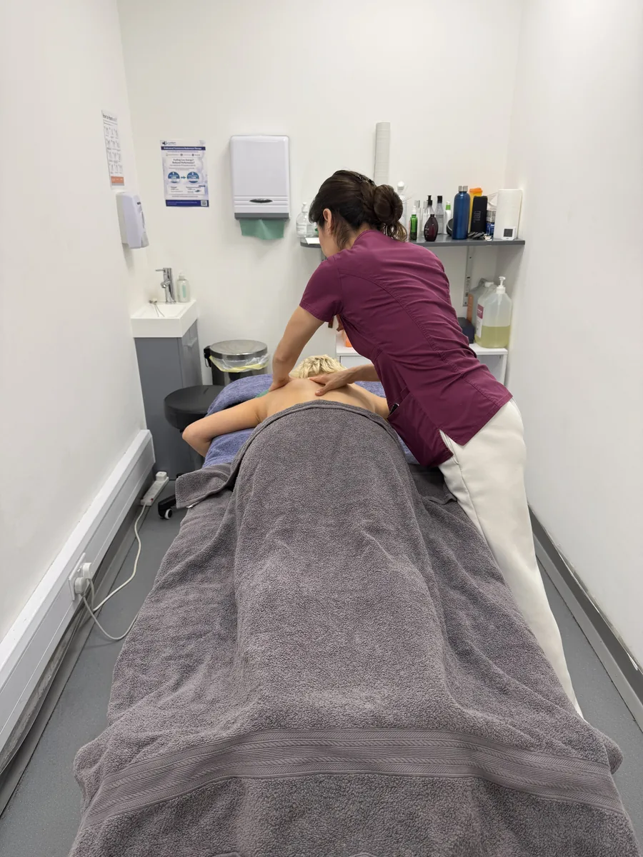 Sports massage therapist working on a player's forearm and shoulder